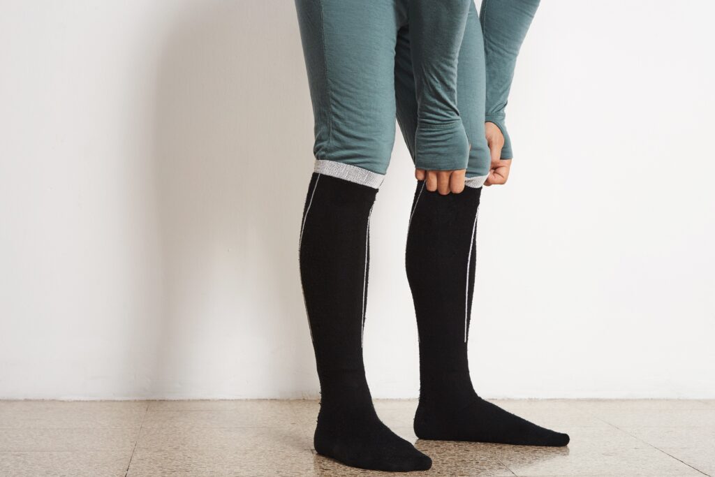legs of male athlete in winter baselayer and black long thermal socks